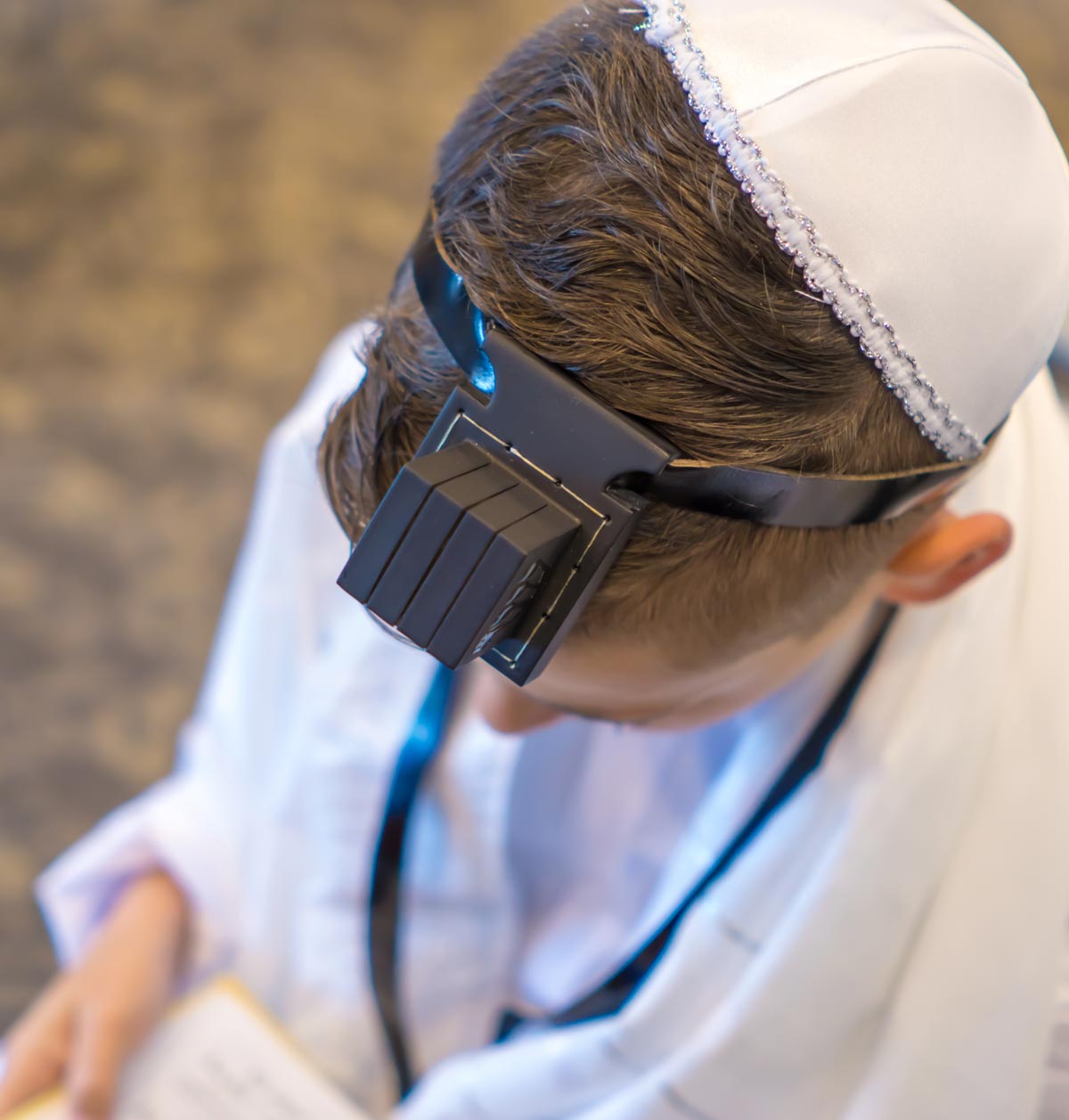 Boy wearing tefillin and a kippah reading from a prayer book at his Bar Mitzvah - Snappy Photobooths