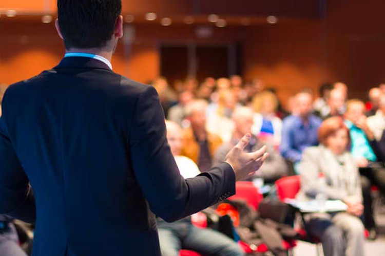 Presenter addressing a seated audience at a corporate conference - Snappy Photobooths