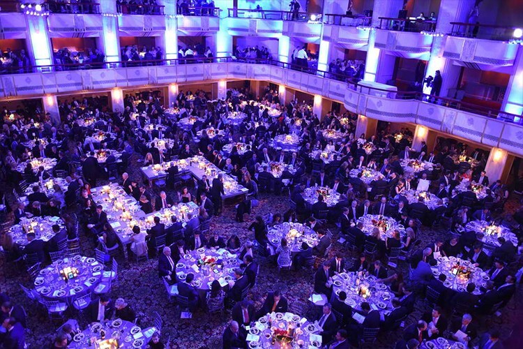Guests seated at round tables in a grand ballroom during a fundraiser gala dinner - Snappy Photobooths