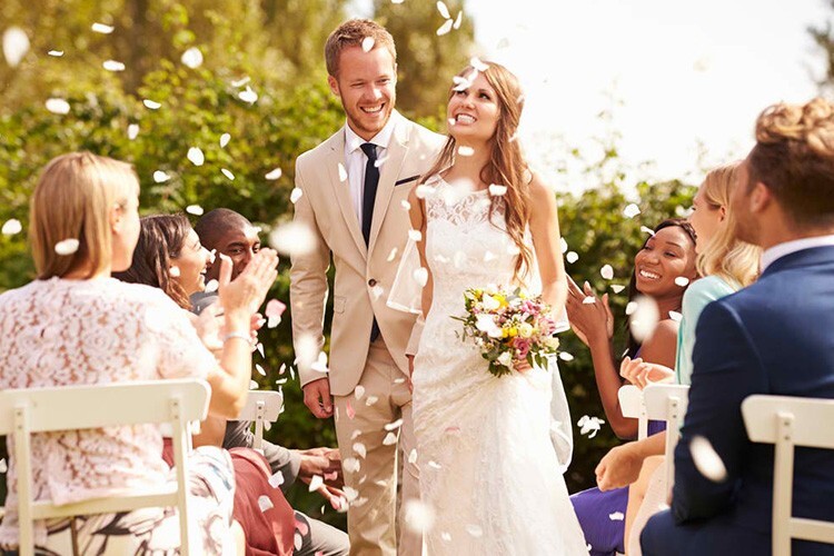 Bride and groom walking through confetti at their wedding ceremony - Snappy Photobooths