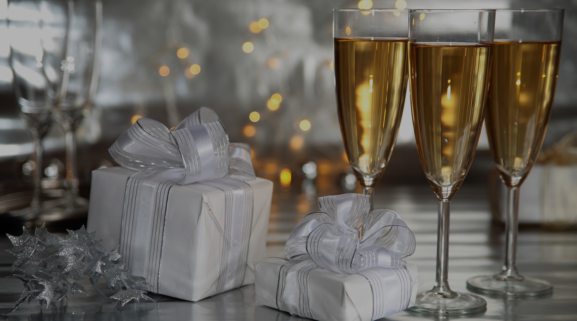 Wrapped gifts with silver bows and champagne glasses at an anniversary celebration - Snappy Photobooths